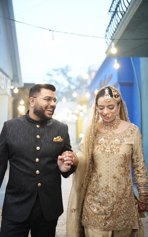 Groom in black sherwani with his bride in gold lehenga
